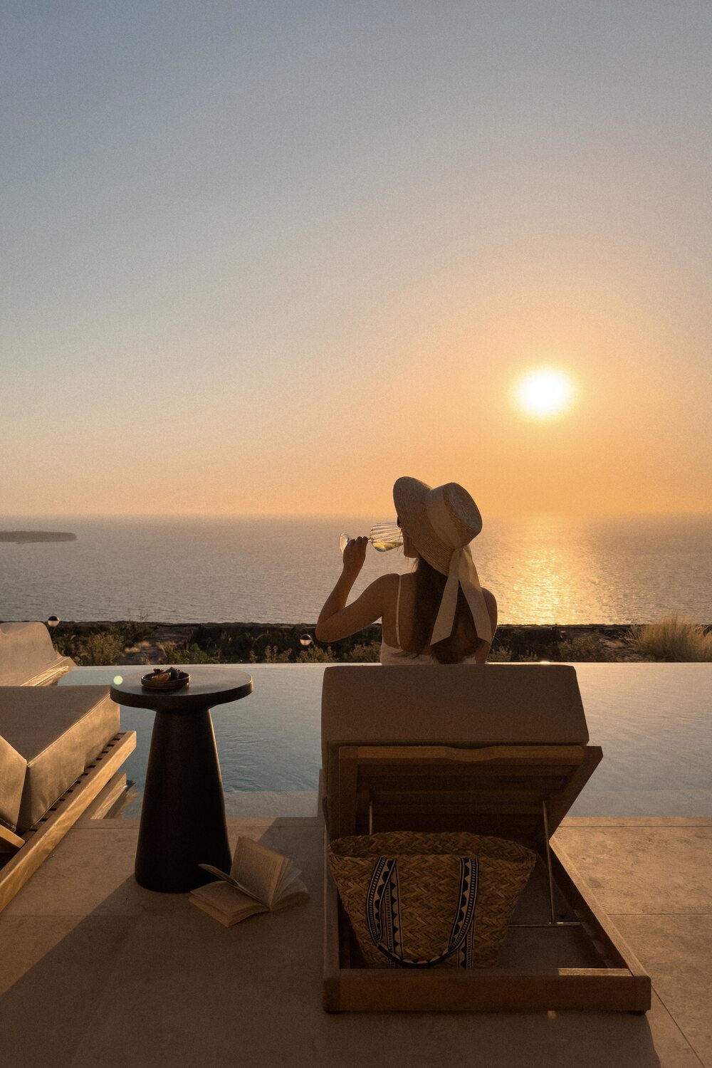 Jessie sipping wine on sunbed of terrace in suite while the sunsets